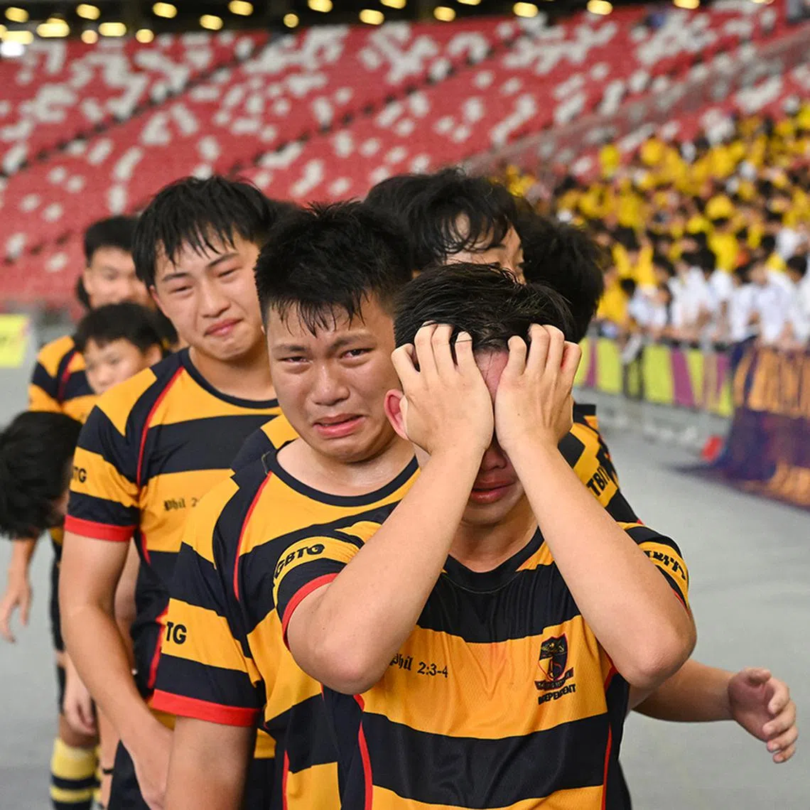 Anglo-Chinese School (Independent)’s B Division rugby captain Jansen Ling holding back his tears alongside emotional teammates before collecting their gold medal at the National Stadium on May 6. They beat St Andrew’s 15-11 in the final to reclaim the title they last won in 2022. ST PHOTO: AZMI ATHNI