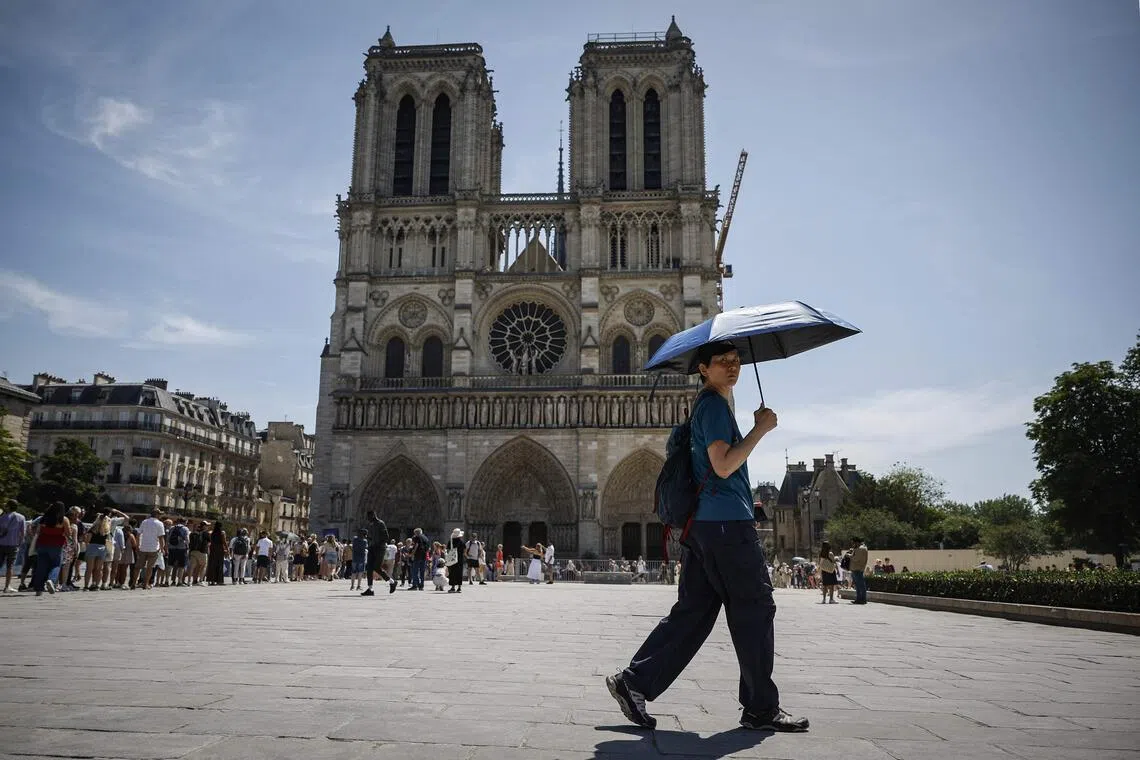 A tourist sheltering from the sun under an umbrella in front of Notre-Dame Cathedral in Paris on May 28.