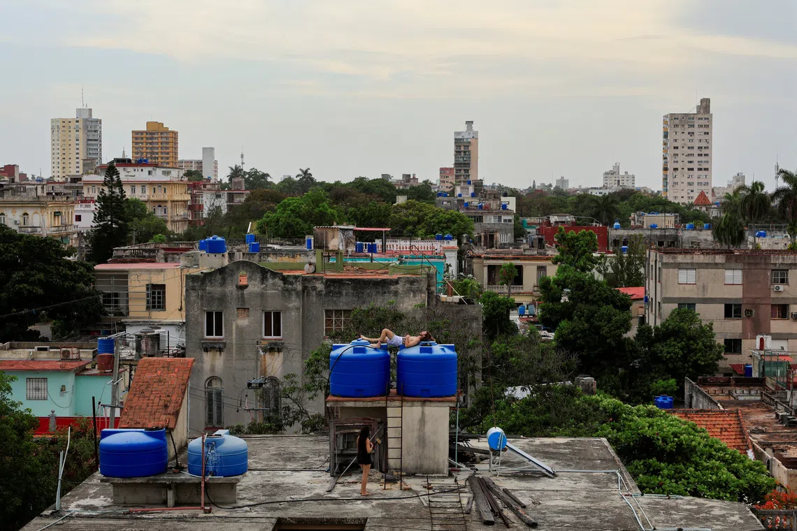 A man rests on water tanks as Cuba's grid operator UNE said it had reconnected most of the country to the national grid, though millions remained without power as the country struggles to generate even one-third of current demand amid an ongoing U.S. fuel blockade, in Havana, Cuba, July 7, 2026. REUTERS/Norlys Perez