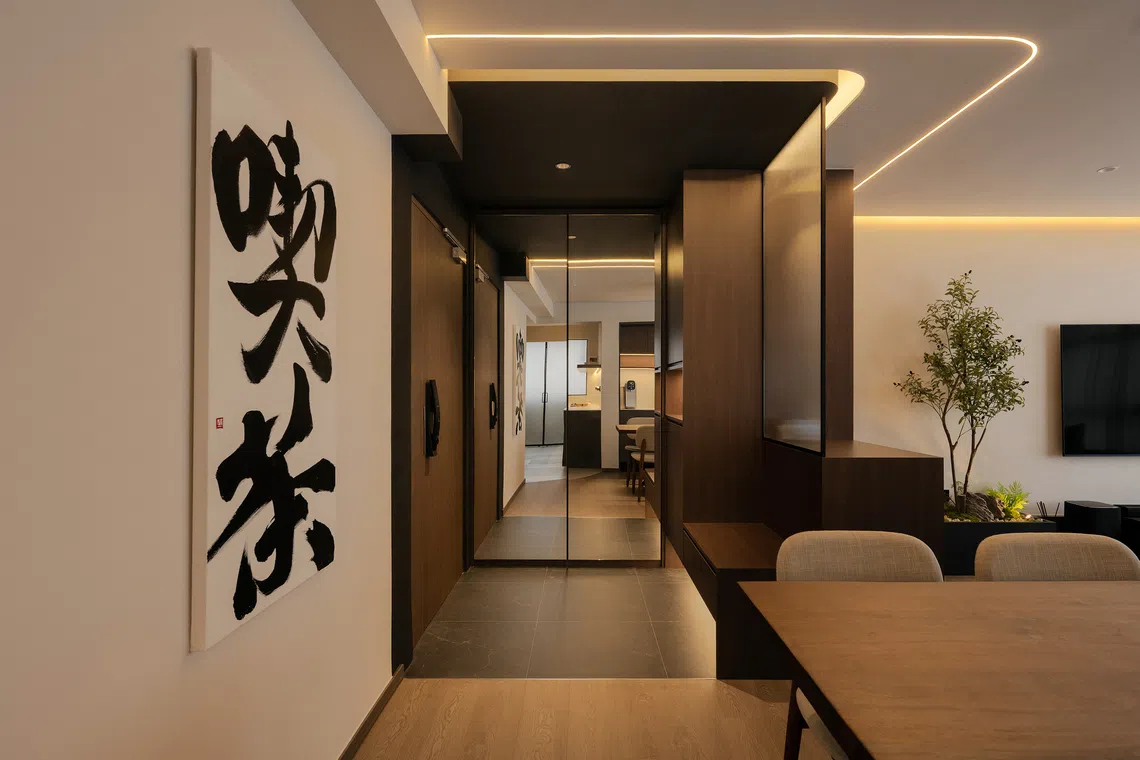 The foyer has a divider comprising storage cabinets, a niche for keys and other small essentials, a settee for putting on shoes and a fluted-glass screen that lets in light while preserving privacy. 