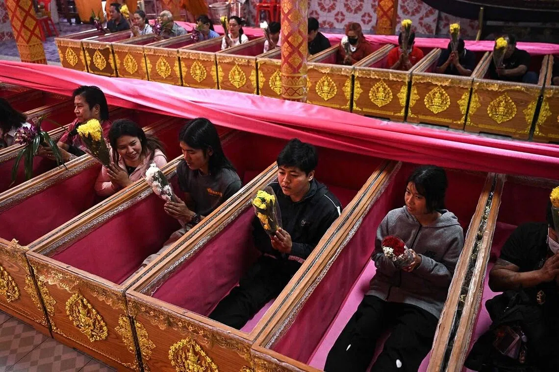People praying in coffins during a resurrection ceremony where devotees lie in coffins for a symbolic death before being reborn, at Wat Ta Kien Buddhist temple in Nonthaburi, Thailand, on Jan 1, 2026. 