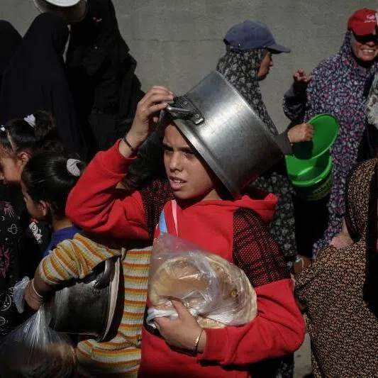 Displaced Palestinians, children and adults, waiting for food at a shelter in Nuseirat, central Gaza on Nov 23.
