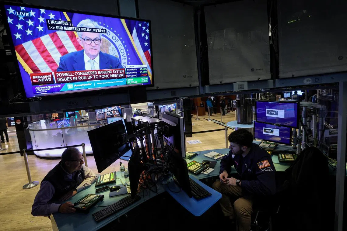 Traders work on the floor of the New York Stock Exchange, as US Federal Reserve chairman Jerome Powell delivers remarks onscreen.