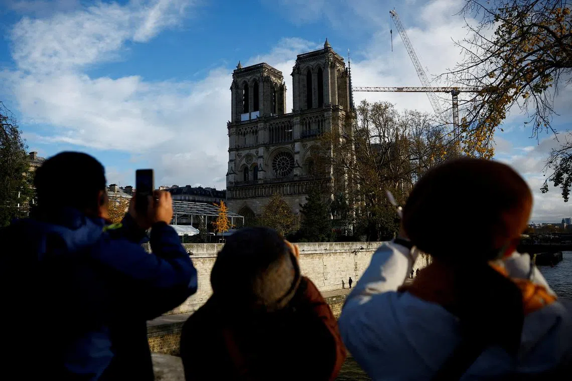 FILE PHOTO: Tourists take pictures of the Notre-Dame de Paris Cathedral, which was ravaged by a fire in 2019, as restoration works continue before its reopening, in Paris, France, November 22, 2024. REUTERS/Sarah Meyssonnier/File Photo