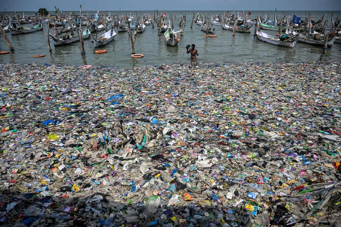 A fisherman returning to the shore amid trash on the beach in Bangkalan, Madura Island, East Java province on May 13, 2024. 