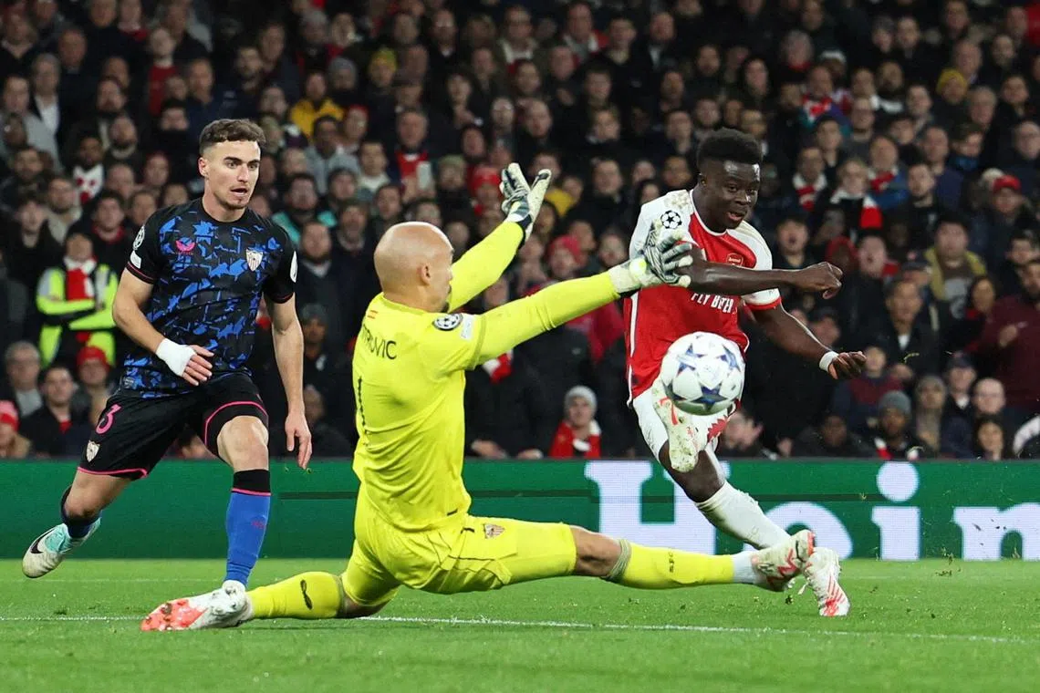 Arsenal's Bukayo Saka scores their second goal past Sevilla's Marko Dmitrovic in their 2-0 Champions League win.