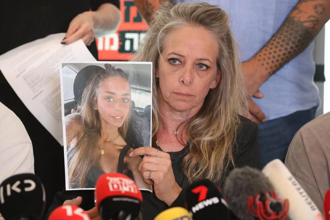 Keren Shelf, the mother of Israeli-French citizen Mia Shem, who is among some 200 people being held hostage by Hamas in Gaza, holds up a picture of her daughter during a press conference in Tel Aviv, Israel on October 17, 2023. Hamas published a video October 16 showing Mia receiving medical treatment for a wound to her arm in captivity, claiming she was abducted from the site of a music festival where at least 260 people were killed.  