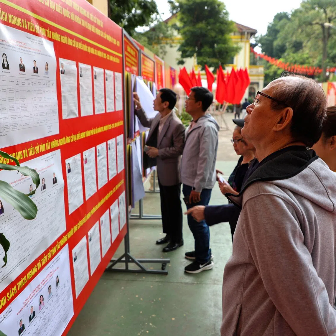 People look at a board with information about candidates outside a polling station during a parliamentary election, in Hanoi, Vietnam, March 15, 2026.