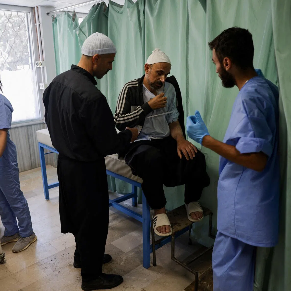 A health worker assists a man at a hospital, following deadly clashes between Druze fighters, Sunni Bedouin tribes and government forces, in Syria's predominantly Druze city of Sweida, Syria July 25, 2025. REUTERS/Khalil Ashawi