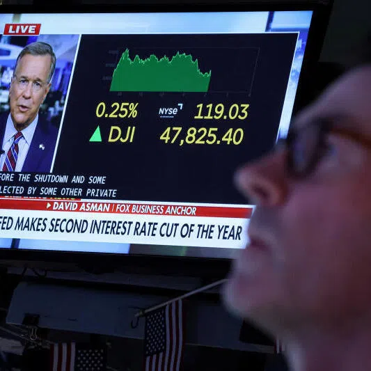 A screen displays a headline about the US Federal Reserve rate cut announcement as a trader works on the floor of the New York Stock Exchange in New York City.
