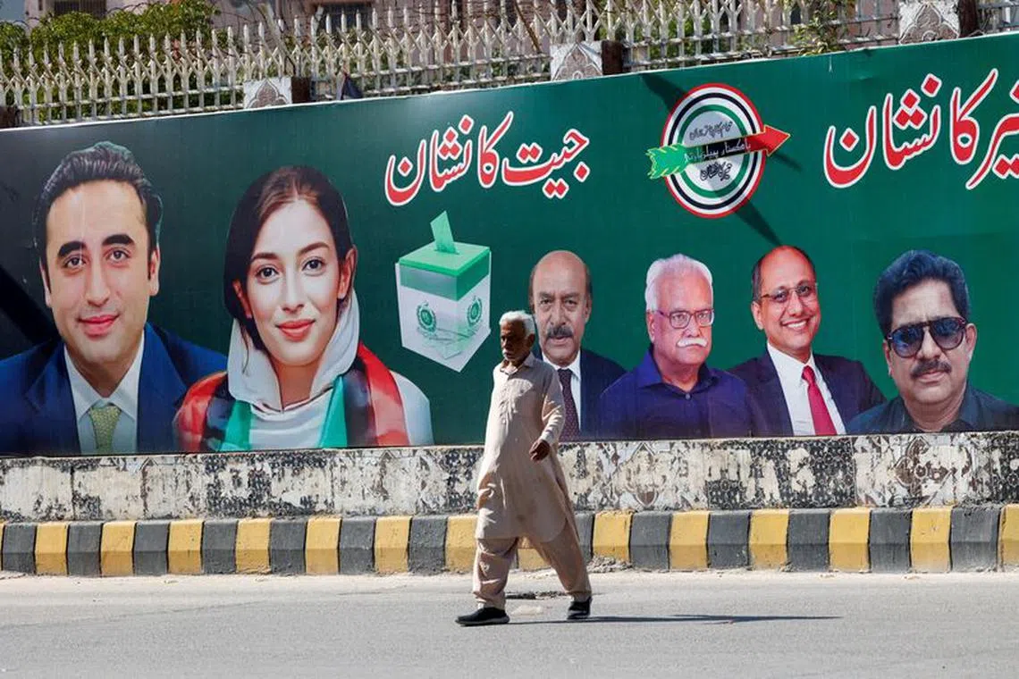 FILE PHOTO: A man walks next to a billboard displaying photos of politician Bilawal Bhutto and his sister Asifa Bhutto, a day after general elections in Karachi, Pakistan February 9, 2024. REUTERS/Akhtar Soomro/File Photo