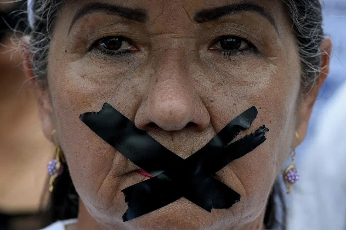 TOPSHOT - A relative of a political prisoner takes part in a march with her mouth covered with black tape to denounce recent deaths in custody and demand urgent protection for detainees in Caracas, May 20, 2026. (Photo by Federico PARRA / AFP)