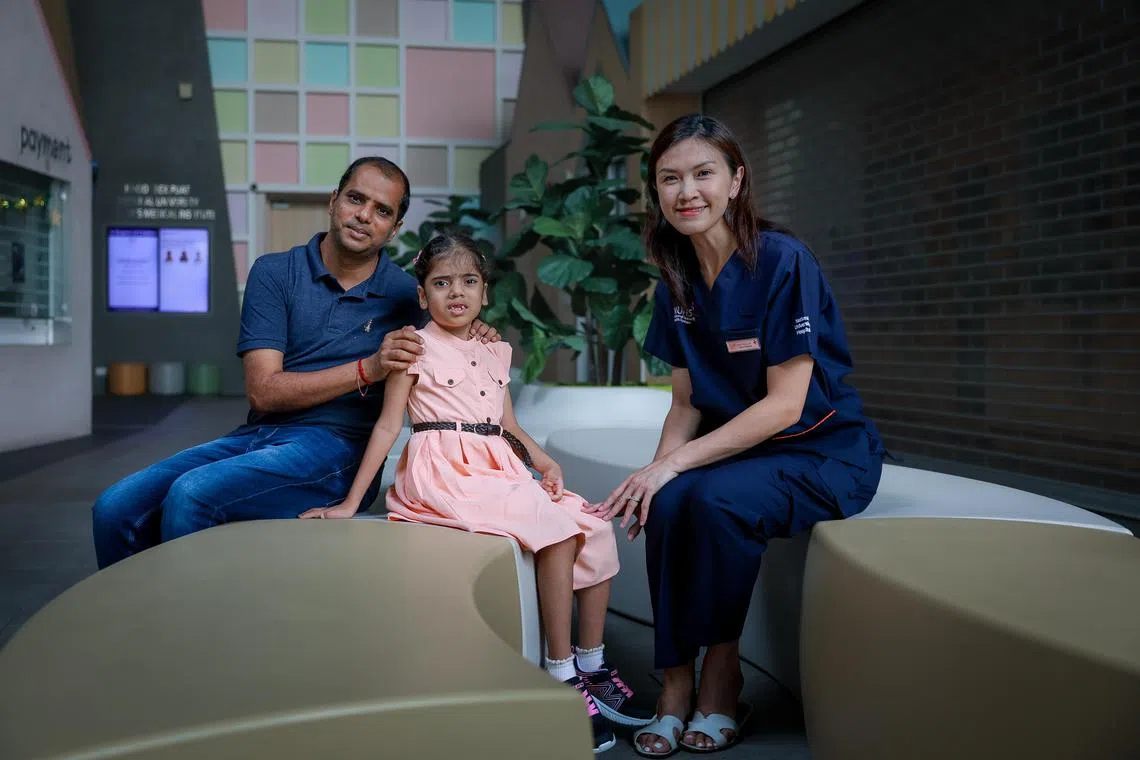 Mr Veerama Rao with his daughter Geethika Rao, 7, and her doctor Dr Chin Hui-Lin, Senior Consultant, Division of Genetics and Metabolism, Department of Paediatrics, Khoo Teck Puat - National University Children's Medical Institute, National University Hospital, at the hospital on March 29, 2025. Geethika suffers from Smith-Magenis Syndrome,