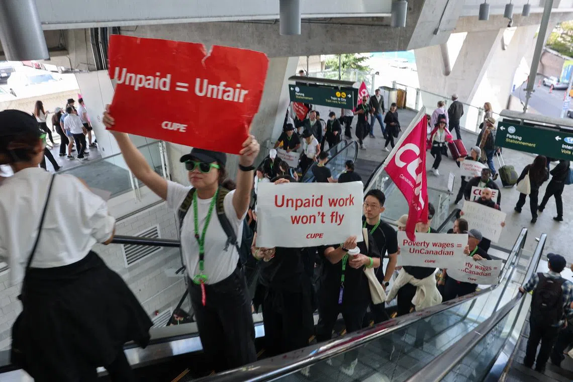 FILE PHOTO: Demonstrators display placards while riding an escalator as Air Canada flight attendants said they will remain on strike and challenge a return-to-work order they called unconstitutional, defying a government decision to force them back to their duties, at Vancouver International Airport in Richmond, British Columbia, Canada, August 17, 2025.  REUTERS/Chris Helgren/File Photo