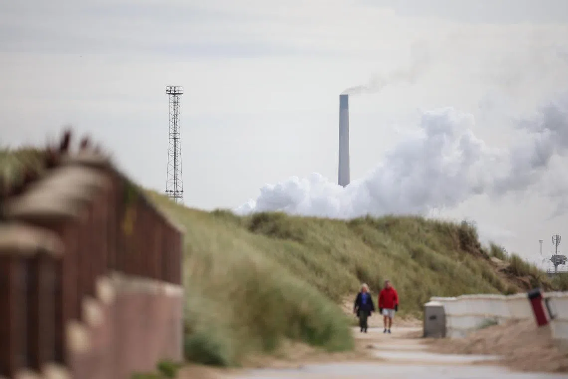 epa10922009 People walk along the promenade in view of the Tata steelworks in Port Talbot, Britain, 16 October 2023. A GBP500 (EUR577) million government support package was announced in September 2023 to help secure the future of the Port Talbot steelworks, with Tata Steel investing over GBP700 (EUR808) million. The deal is expected to result in up to 3,000 job losses as the company transitions from coal-powered blastfurnaces to less labour intensive electric arc furnaces in a bid to reduce costs and decarbonise the production process. Tata employ around 8,000 people in the UK, of which 4,000 are based at Port Talbot.  EPA-EFE/ADAM VAUGHAN