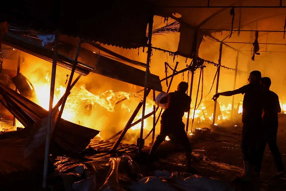 People attempt to extinguish a fire at the site of an Israeli strike on tents sheltering displaced people, amid the Israel-Hamas conflict, in Deir Al-Balah in the central Gaza Strip, October 14, 2024. REUTERS/Ramadan Abed TPX IMAGES OF THE DAY