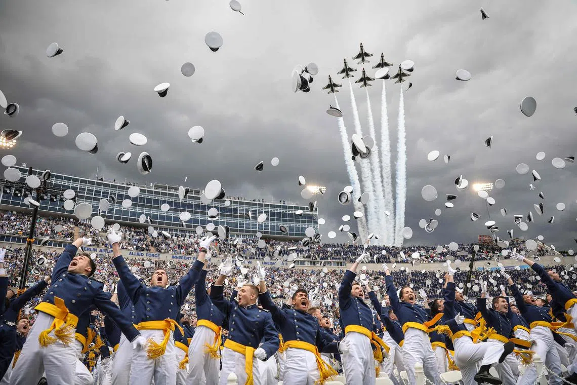 Air Force Academy cadets throw their caps into the air upon graduating as the Thunderbirds fly over Falcon Stadium on June 1, 2023, on the grounds of the U.S. Air Force Academy in Colorado Springs, Colorado. 