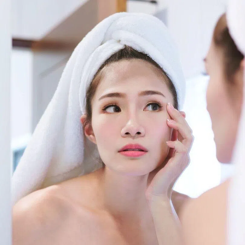 Pretty Asian woman looking at herself in the mirror