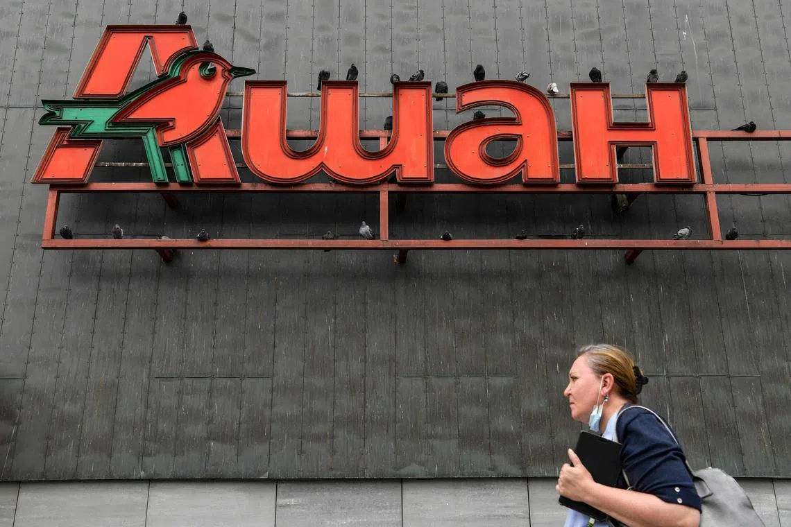 The logo of French supermarket Auchan is pictured on the wall of a shopping mall in Moscow. Auchan has kept its 230 stores in Russia open and says it intends to stay.
