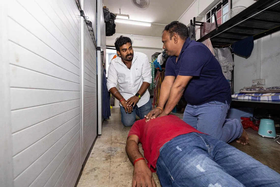 (From left) Mr Karunanithi Prabhakaran guiding Mr Ganapathi Kaliyamoorthy how to perform cardiopulmonary resuscitation (CPR) on Mr Mohan Satheesh Kumar in a demonstration.