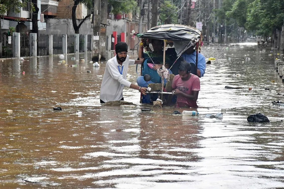 TOPSHOT - Residents wade through a flooded street following heavy monsoon rains in Guwahati on August 4, 2026. (Photo by Biju BORO / AFP)