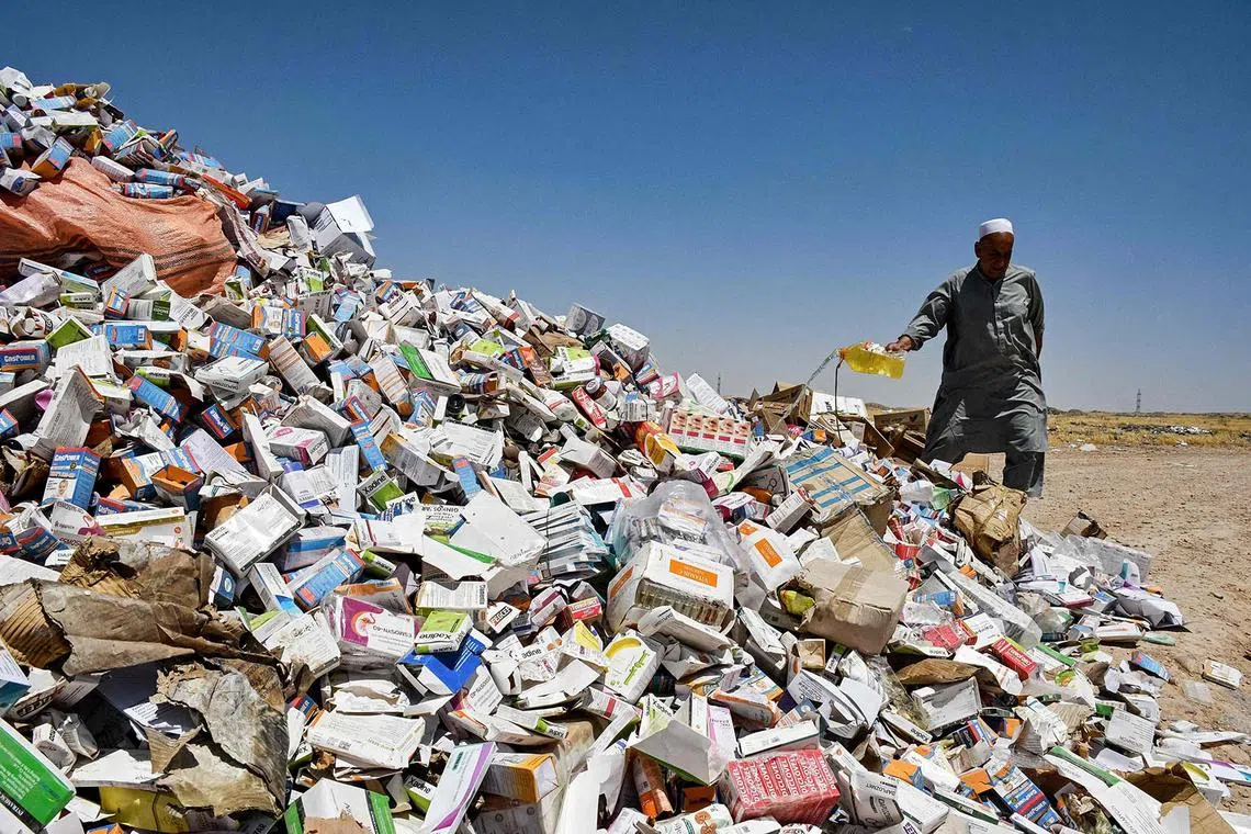 An Afghan official pouring a chemical to set aflame a heap of seized and expired medicines at a field on the outskirts of Mazar-i-Sharif on June 2, 2025. 
