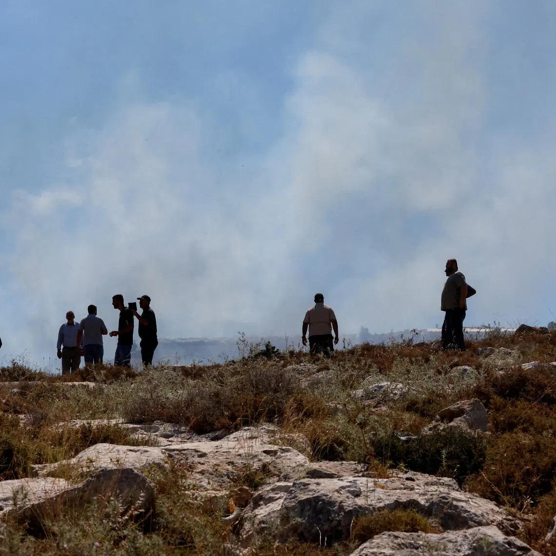 Palestinians observe smoke rising from a fire started by crowd control grenades thrown by Israeli troops, during a protest against a settlement near Hebron in the Israeli-occupied West Bank, June 9, 2026. REUTERS/Mussa Qawasma