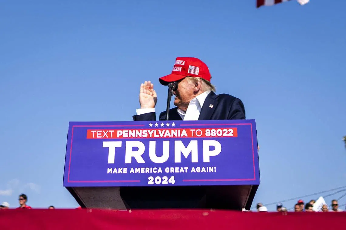 Donald Trump inspecting his hand after touching his ear, as he speaks at a campaign rally.