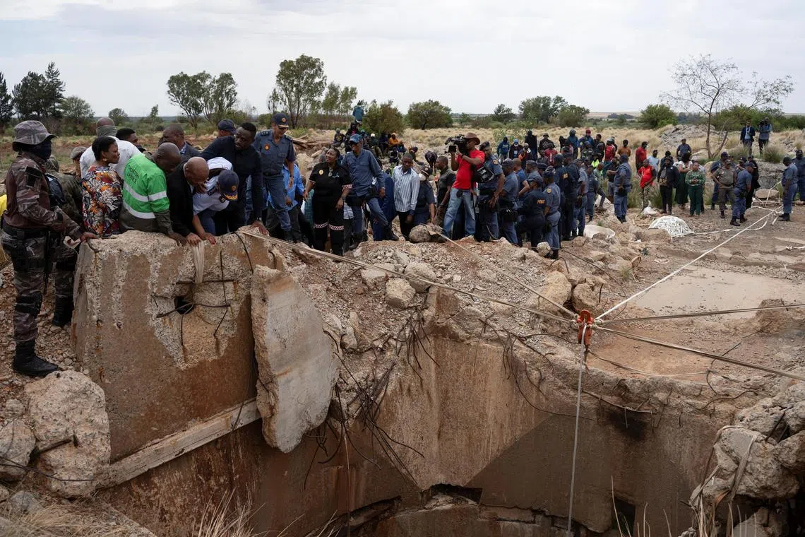Community members watch as Mr Senzo Mchunu, South African police minister, inspects outside the mineshaft where it is estimated that hundreds of illegal miners are believed to be hiding underground in Stilfontein, South Africa, on Nov 15.