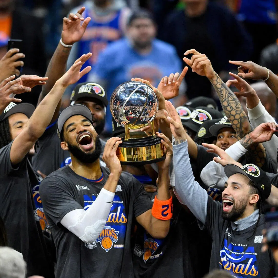 New York Knicks center Karl-Anthony Towns lifts the 2026 Eastern Conference trophy with teammates after defeating the Cleveland Cavaliers.