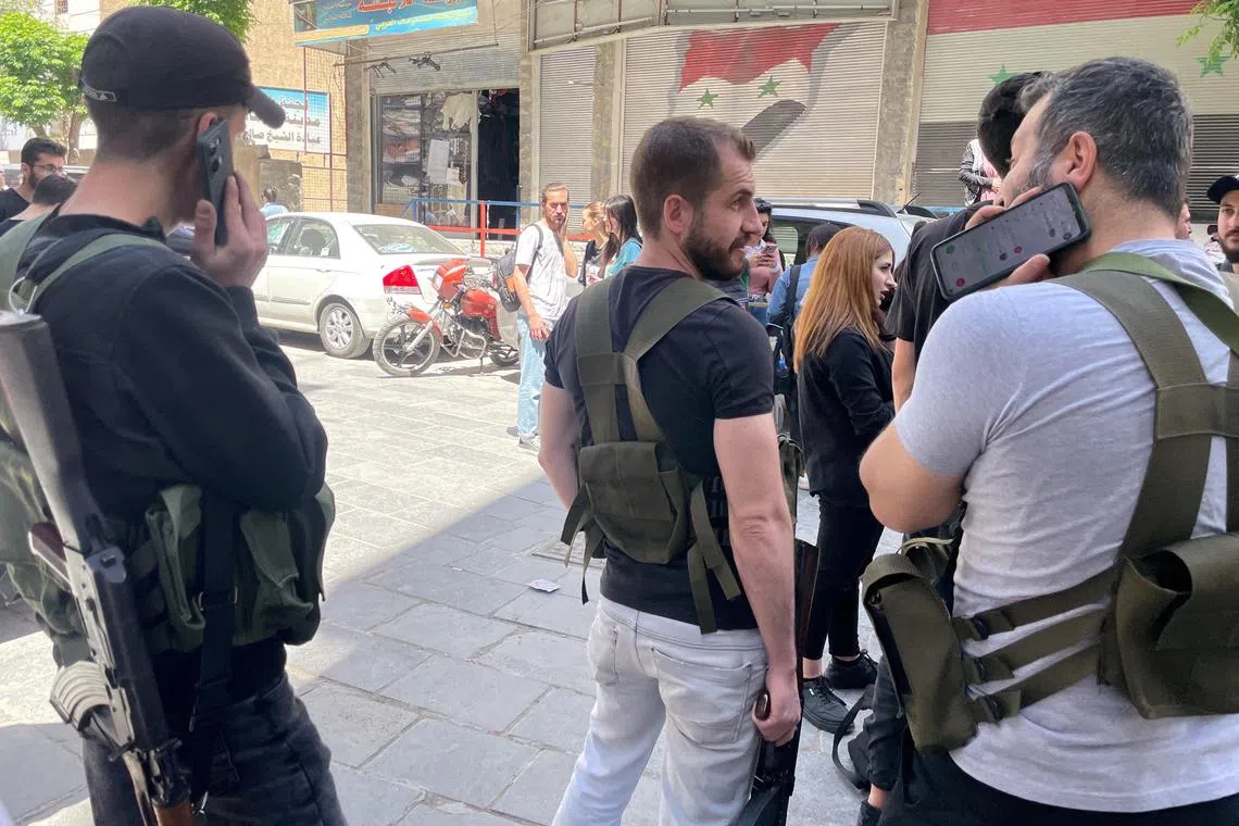 Armed Druze men stand at a checkpoint in Jaramana, south-east of Damascus, Syria.