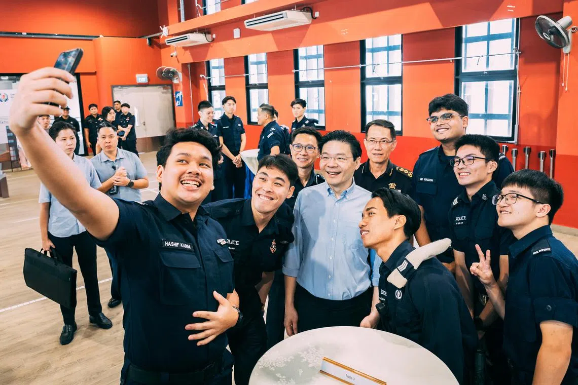 Prime Minister Lawrence Wong posing with Home Team officers for a wefie during a visit to Punggol Neighbourhood Police Centre and Punggol Fire Station on April 4.