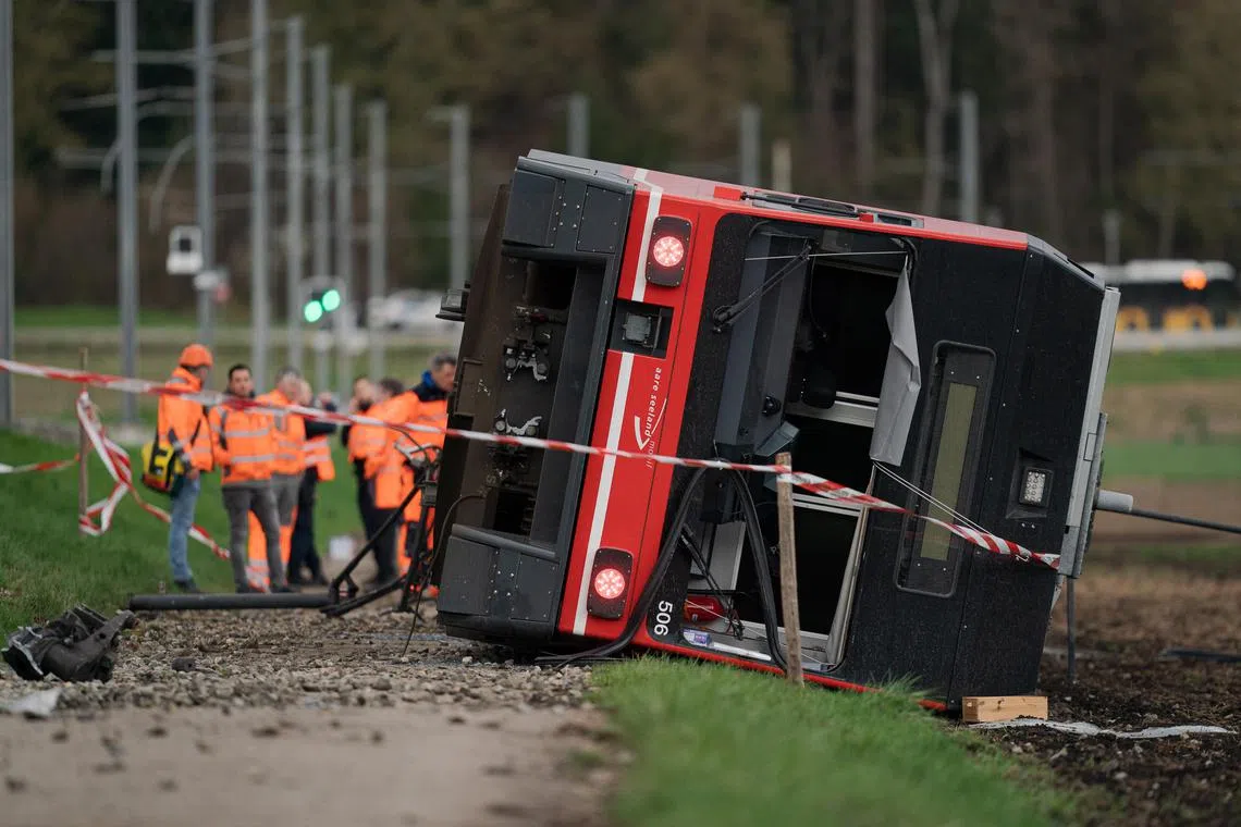 Emergency workers inspect the site of a derailed train in the Swiss lakeside town of Luscherz.