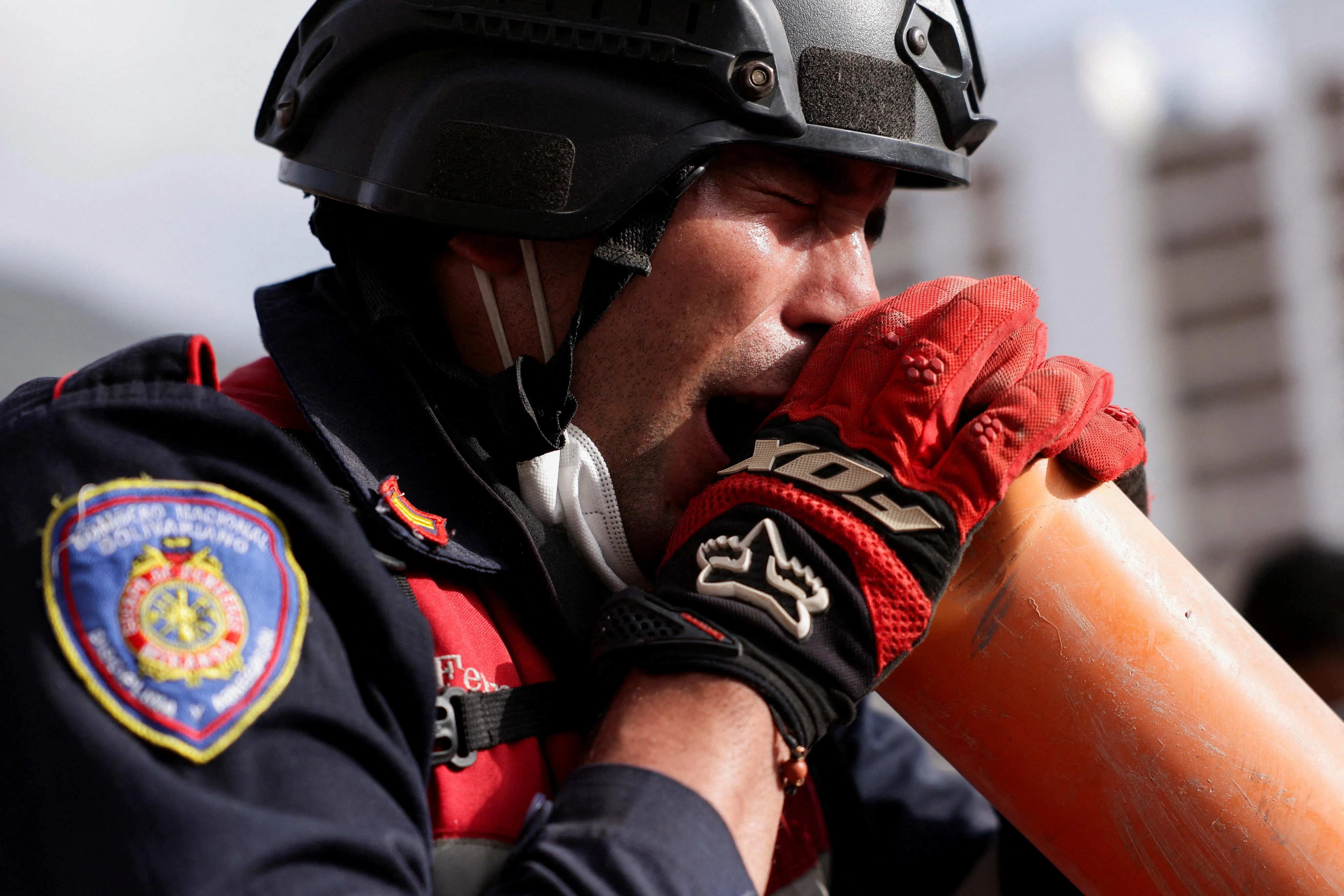 A firefighter screams through a tube to the people under the rubble of a collapsed building after earthquakes hit the country, in La Guaira, Venezuela, June 26, 2026. REUTERS/Gaby Oraa