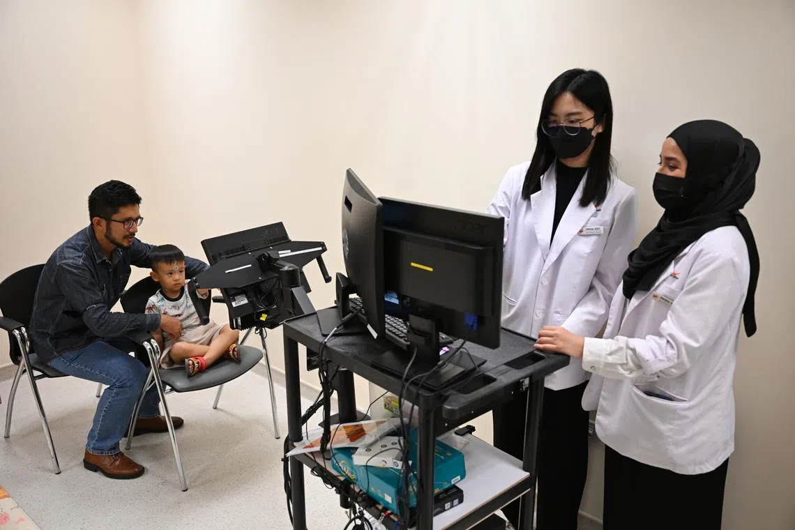 Clinical research coordinators conducting a demonstration of a research study on a child to study the time he takes to react to a stimulus.