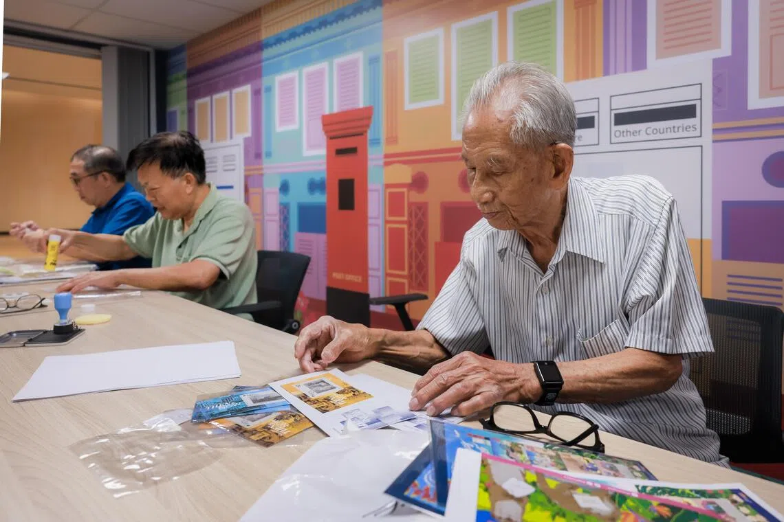 Stamp collectors Tan Kan Buey and Eddie Yong (in green) reviewing the lenticular stamps.