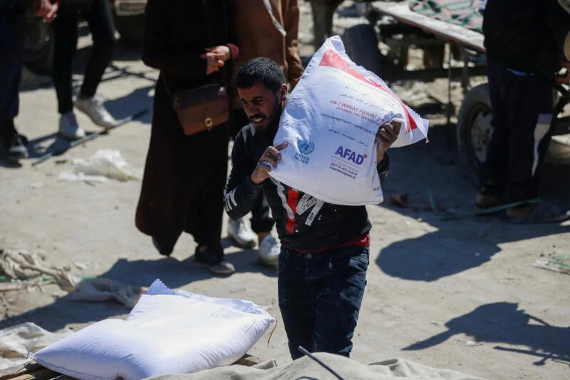 A man carries a sack as Palestinians gather to receive aid provided by UNRWA including food supplies, after Israel says it has ceased entry of humanitarian aid into Gaza, outside a distribution center, at Jabalia refugee camp in northern Gaza Strip, March 2, 2025. REUTERS/Mahmoud Issa