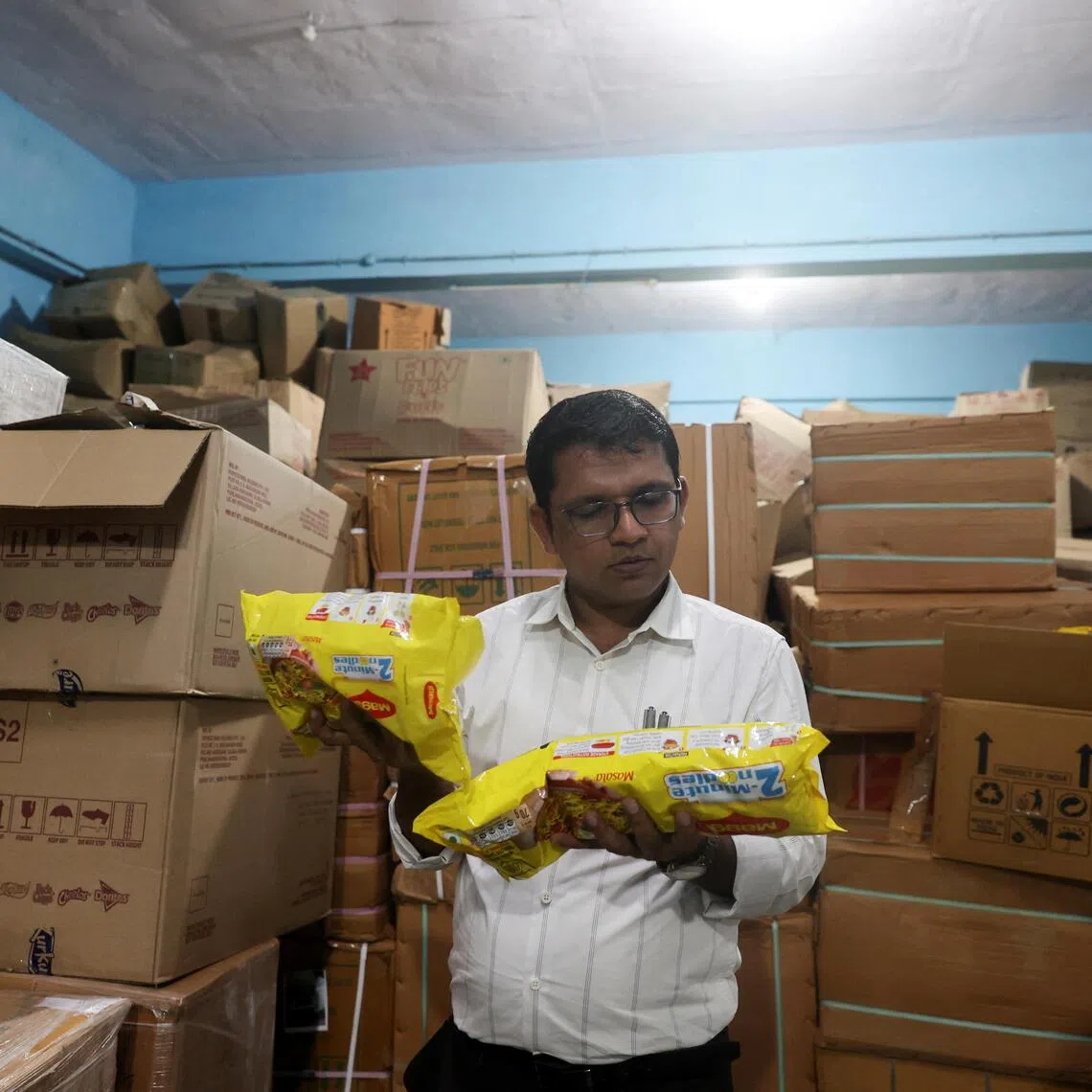 A Maharashtra Food and Drug Administration official inspects labels on packets of Maggi noodles and ingredient lists during a raid at a warehouse in Turbhe, India, on Aug 25.
