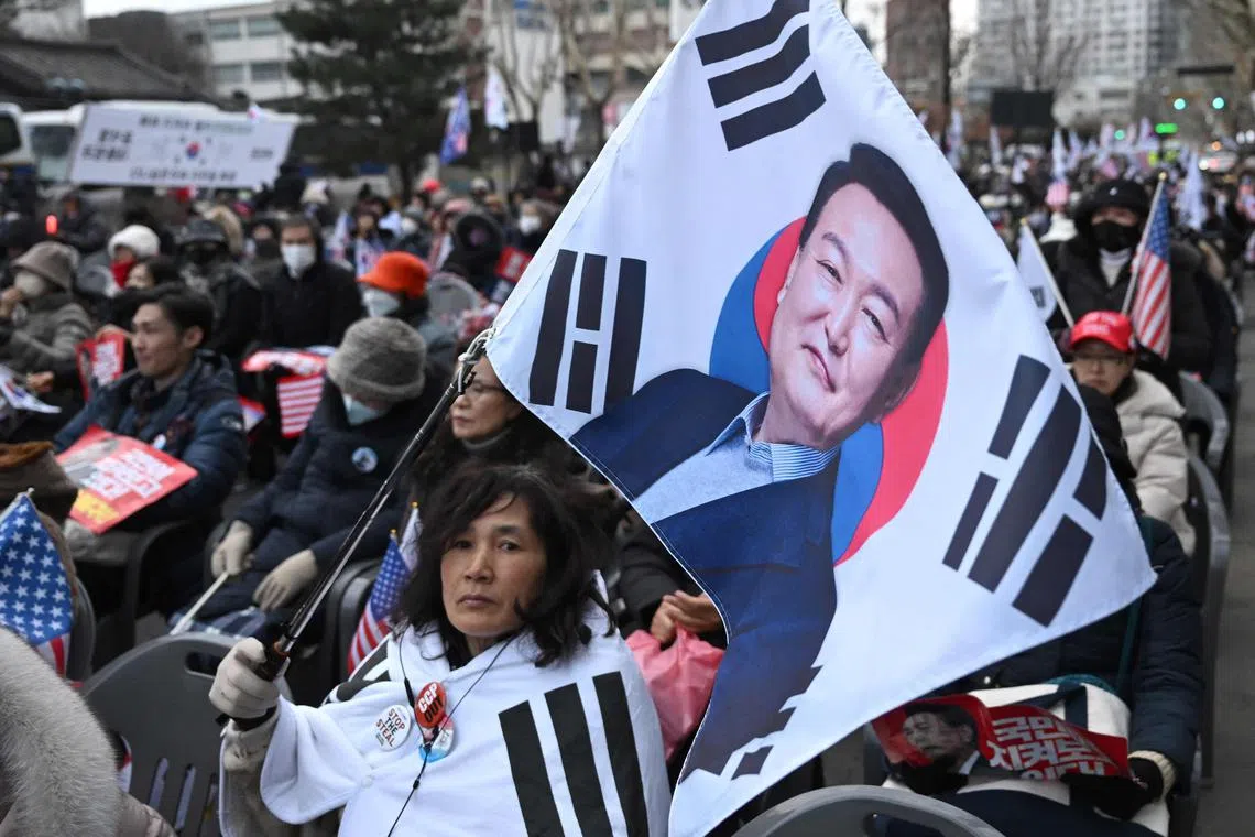 A supporter of South Korea President Yoon Suk Yeol waves a flag showing a picture of Yoon during a rally near the Constitutional Court in Seoul on February 25, 2025, as Yoon is scheduled to attend his final impeachment hearing. (Photo by Jung Yeon-je / AFP)