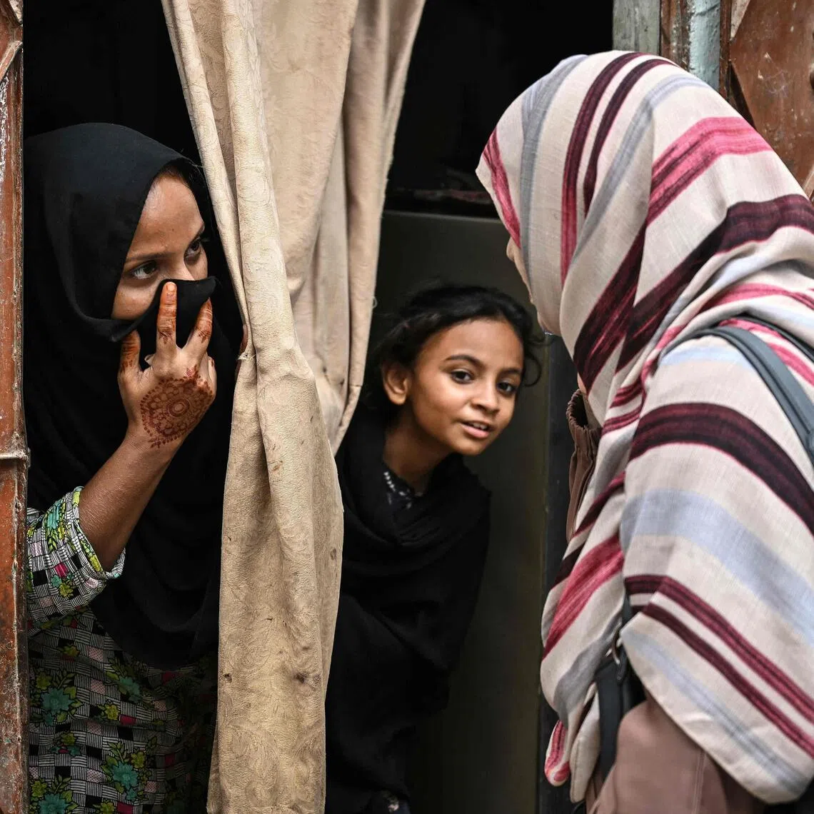 A health worker (R) speaks with a woman and her daughter in Karachi on September 24, 2025, during a door-to-door human papillomavirus (HPV) vaccination drive against cervical cancer, most frequently diagnosed in women. Misinformation about a vaccine campaign to protect Pakistani girls against cervical cancer led parents to slam their doors in the faces of healthcare workers and schools to shut for days in an attempt to stymie the effort. (Photo by Rizwan TABASSUM / AFP)