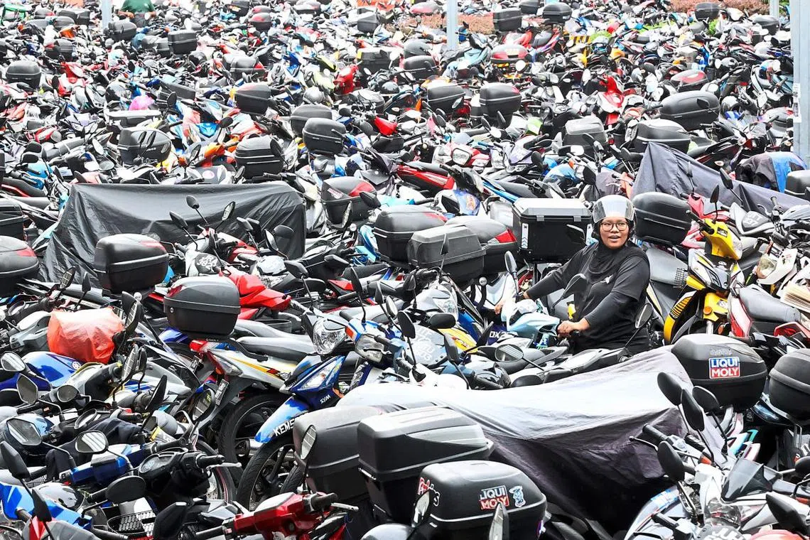 Single mother Effa Suraya A. Hamid, 42, trying to navigate her way out of a crammed makeshift motorcycle parking lot located near the main entrance of the Bangunan Sultan Iskandar Customs, Immigration and Quarantine Complex (BSI CIQ) in Johor Baru. Daily commuters park their motorcycle here daily before hopping on the bus to cross into Singapore for work. — THOMAS YONG/The Star
