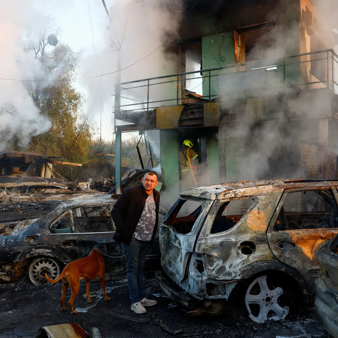 A resident with a dog looks on at the site of private car garages hit by a Russian missile strike, amid Russia's attack on Ukraine, in Kyiv, Ukraine October 7, 2026. REUTERS/Valentyn Ogirenko     TPX IMAGES OF THE DAY