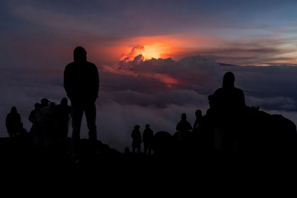FILE PHOTO: People gather to watch the eruption of the Mauna Loa Volcano while the lava flow is covered with the clouds in Hawaii, U.S. December 3, 2022.  REUTERS/Go Nakamura/File Photo