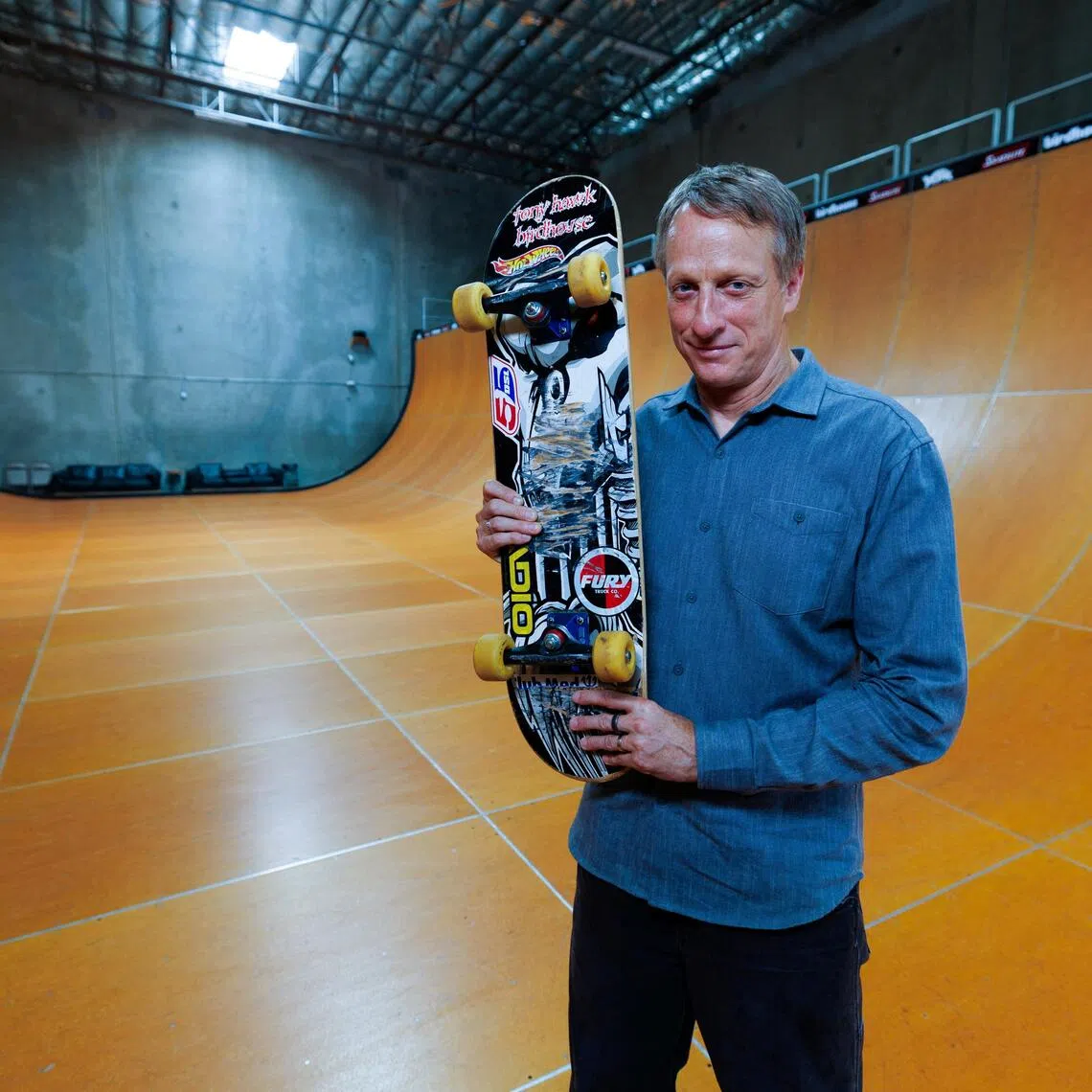 Tony Hawk holds the skateboard he used to land the first-ever "900" at the 1999 X Games, a milestone that transformed skateboarding from subculture to global sport and made Hawk its defining icon.