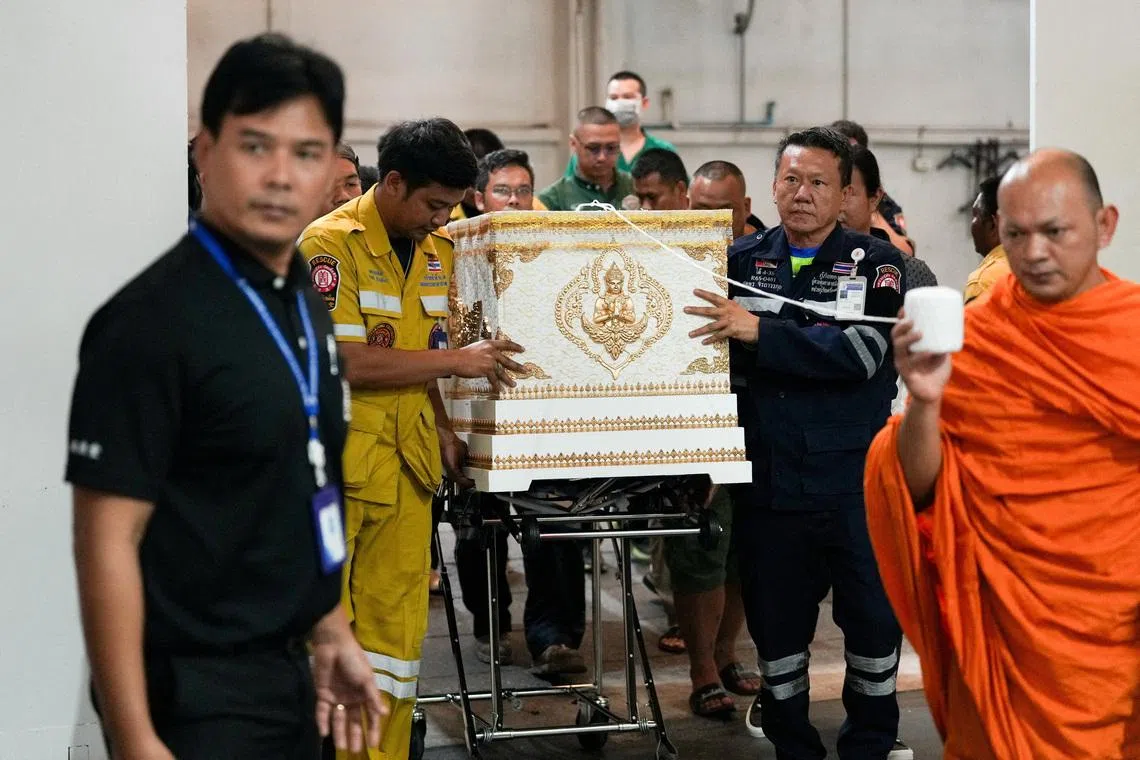 Emergency services members move a coffin with the body of a victim at the Police Hospital morgue, following a deadly fire at a pub in Bangkok, Thailand, July 13, 2026. REUTERS/Arnun Chonmahatrakool