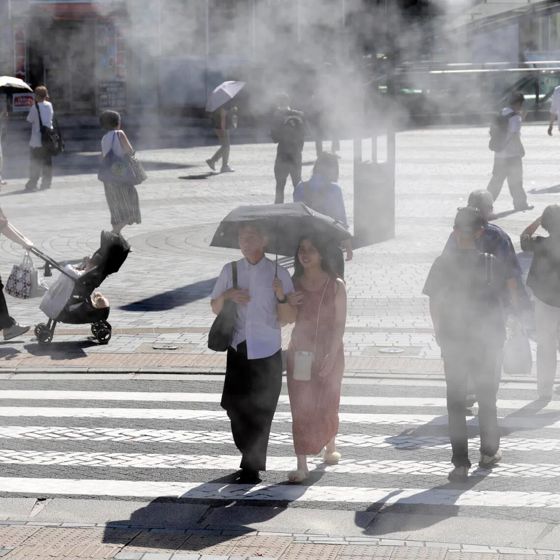 People walk past a cooling mist station during a heatwave in Tokyo on Aug 24.