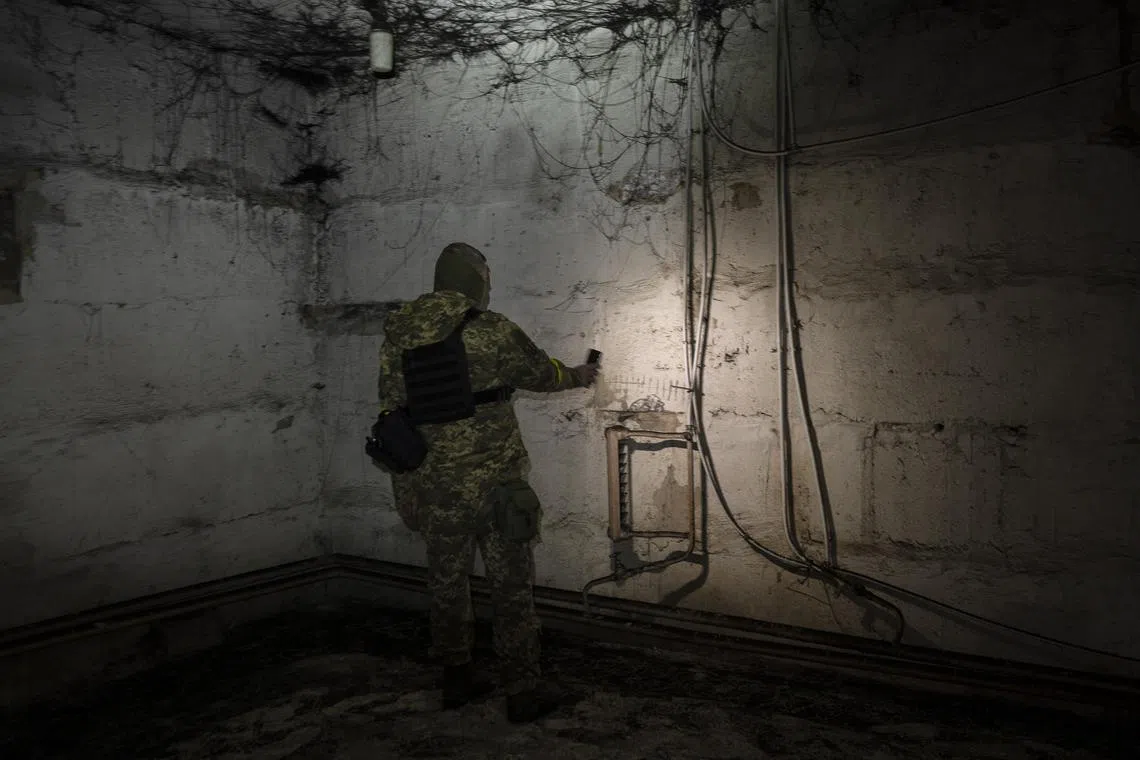 A member of the Ukrainian security forces inspects a basement used as a prison.