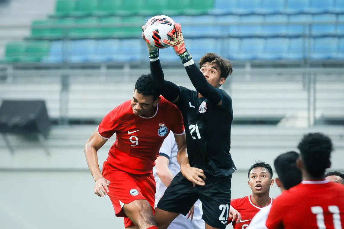 Singapore’s Jordan Emaviwe (No. 9, red) challenging for the ball with Cambodia goalkeeper Reth Lyheng in the Merlion Cup third-placing match at Jalan Besar Stadium on March 26, 2023.