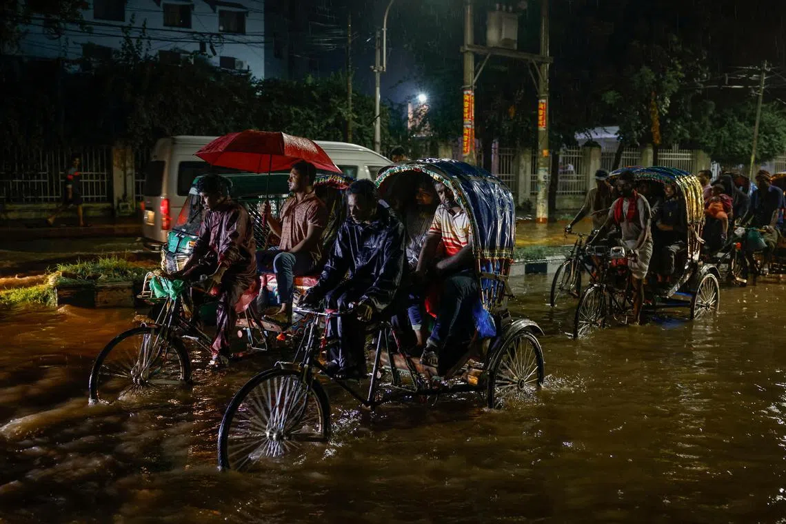 Commuters move on rickshaws through a flooded street after the downpour at night in Dhaka, Bangladesh, on Oct 2.