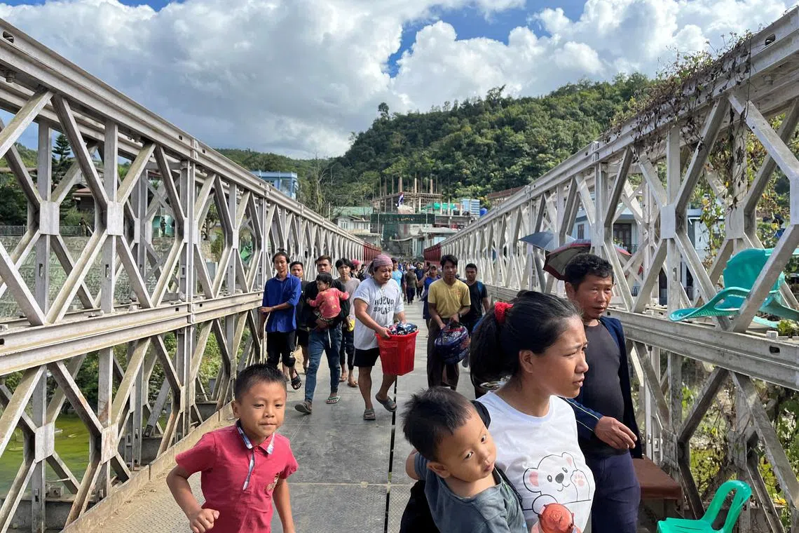 People who fled Myanmar carry their belongings across a bridge that connects Myanmar and India at the border village of Zokhawthar.